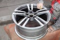 Master body repair man is working on preparing the surface of the aluminum wheel of the car for subsequent painting in the