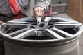 Master body repair man is working on preparing the surface of the aluminum wheel of the car for subsequent painting in the