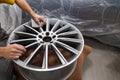 Master body repair man is working on preparing the surface of the aluminum wheel of the car for subsequent painting in the Royalty Free Stock Photo