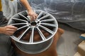 Master body repair man is working on preparing the surface of the aluminum wheel of the car for subsequent painting in the