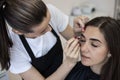 The master corrects the shape of the eyebrows with tweezers after waxing