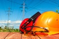 For the master builder protective helmet, headphones, gloves on wooden table, against the background of nature and high voltage