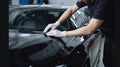 The master in the car service applies a protective armor film to the car body