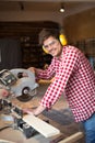 Master carpenter with headphones and glasses saws board circula