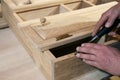 master carpenter works with a hand tool with a chisel, sets the hinges on the cabinet. Production of handmade wooden furniture.