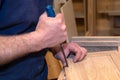 master carpenter works with a hand tool with a chisel, sets the hinges on the cabinet. Production of handmade wooden furniture.