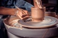 Master-ceramist creates a clay pot on a potter`s wheel. Hands of potter close up. Ancient craft and pottery handmade