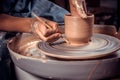 Master-ceramist creates a clay pot on a potter's wheel. Hands of potter close up. Ancient craft and pottery handmade