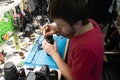 Master checks and repairs photo equipment in repair shop. Selective focus on male hands holding miniature screwdriver