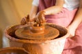 Master class for child. Teacher hands show to kid how make ceramics dishes on potter wheel. Artist works with clay