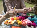 Master-class in mandala weaving. Woman is teaching another woman how to make colorful geometric talisman