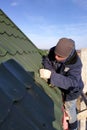 The worker screws the snow retaining elements to the roof with a screwdriver