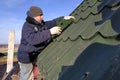 The worker screws the snow retaining elements to the roof with a screwdriver