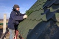 The worker screws the snow retaining elements to the roof with a screwdriver