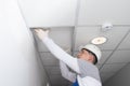 Master of communications maintenance, opens the suspended ceiling, for the repair of lighting and alarm wiring