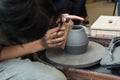 The master creates products from gray clay on a potter& x27;s wheel. Girl creates a ceramic vase