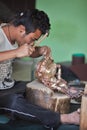 Master in creation of traditional Buddhist bronze statues at work.