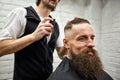 Master cuts hair and beard of men in the barbershop, hairdresser makes hairstyle for a young man Royalty Free Stock Photo