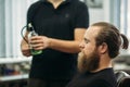 Master cuts hair and beard of men in the barbershop, hairdresser makes hairstyle for a young man