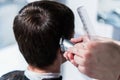 Master cuts hair of men in the barbershop, hairdresser makes hairstyle for a young man