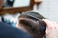 Master cuts hair of men in the barbershop, hairdresser makes hairstyle for a young man