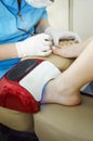 The master does a manicure in the salon, paints the nails with shillak and dries under a special lamp. Closeup. Vertical Royalty Free Stock Photo