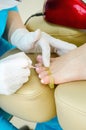 The master does a manicure in the salon, paints the nails with shillak and dries under a special lamp. Closeup. Vertical Royalty Free Stock Photo