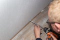 The master drills holes in the wall to install the skirting board. Home and office renovation and improvement