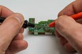 Master engineer tests and repairs microchip with multimeter Royalty Free Stock Photo