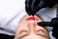 The master erases the remnants of the pigment applied to the lips with a cotton swab