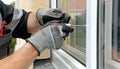 Master in gloves adjusting pvc windows with screwdriver closeup. Installation of plastic windows repair and maintenance Royalty Free Stock Photo