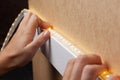 The master glues the LED strip into the niche of the shelf from the cabinet for lighting.installation of diode lighting tape