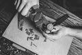 Master holding a hole punch and a piece of leather. On brown wooden table scattered with tools and accessories Royalty Free Stock Photo