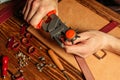 Master holding a hole punch and a piece of leather. On brown wooden table scattered with tools and accessories Royalty Free Stock Photo