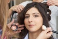 Master inflicts brush powder on the face of the girl, completes the day make-up in a beauty salon.