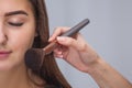 Master inflicts brush powder on the face of the girl, completes the day make-up in a beauty salon. Royalty Free Stock Photo