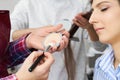 Master inflicts brush powder on the face of the girl, completes the day make-up in a beauty salon. Stylist at this time