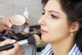 Master inflicts brush powder on the face of the girl, completes the day make-up in a beauty salon. Stylist at this time