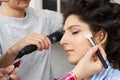 Master inflicts brush powder on the face of the girl, completes the day make-up in a beauty salon. Stylist at this time