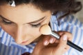 Master inflicts brush powder on the face of the girl, completes the day make-up in a beauty salon. Stylist at this time Royalty Free Stock Photo