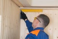 Master for insulation of balconies, checks the angle, for the correctness of the paneling with wooden boards