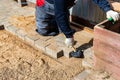 The master in lays paving stones in layers. Garden brick pathway paving by professional paver worker. Laying gray concrete paving Royalty Free Stock Photo