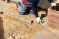 The master in lays paving stones in layers. Garden brick pathway paving by professional paver worker. Laying gray concrete paving