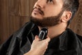 The master makes a beard haircut to the client with an electric machine, trimmer, close-up. The process of shaving a beard at the Royalty Free Stock Photo