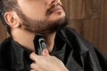 The master makes a beard haircut to the client with an electric machine, trimmer, close-up. The process of shaving a beard at the Royalty Free Stock Photo