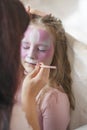 Master making aqua makeup on girl face. Child with funny face art. Royalty Free Stock Photo