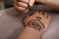 Master making henna tattoo on hand. Traditional mehndi