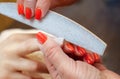 The master of the manicure saws and attaches a nail shape during the procedure of nail extensions with gel in the beauty salon