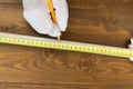 Master measures a piece of white pipe using a tape measure on a wooden background