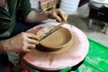 The master measures with a ruler the width of the plate, made to order from red clay. The product is made on a potter`s